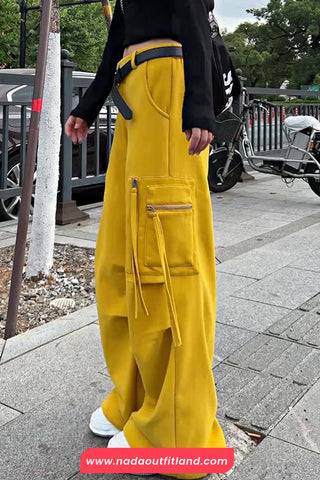 Person wearing yellow pants and a black top on a sidewalk with a blurred background