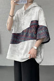 Person wearing a white blouse with patterned sleeves against a gray background