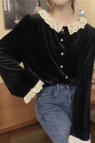 Person wearing a black blouse with lace details and blue jeans indoors.