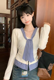 Woman wearing a white long-sleeve top over a blue checkered shirt with a brown bag.