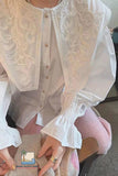White embroidered blouse with ruffled sleeves worn by a person.