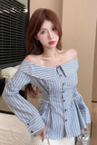 Woman wearing a blue and white striped off-shoulder top in an indoor setting.