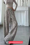 Person wearing leopard print pants in a room with white walls and a fireplace.