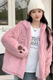 Person wearing a pink fluffy jacket with a teddy bear design, standing outdoors.