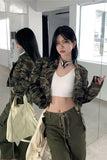Woman in camouflage jacket and white crop top standing in a modern interior setting.