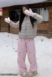 Person wearing a gray puffer jacket and pink checkered pants standing in the snow.