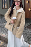 Woman in a beige coat holding a coffee cup on a street.