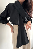 Person wearing a black scarf and beige pants against a white background