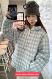 Person wearing a blue and white checkered hoodie taking a selfie in a casual setting.