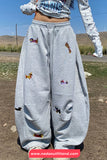 Gray sweatpants with embroidered designs worn outdoors.