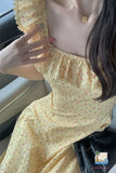 Person wearing a yellow floral dress sitting inside a vehicle.