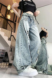 Person wearing oversized light blue jeans and a black crop top in a modern interior setting.