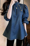 Person wearing a blue denim dress with puffed sleeves in front of a mirror.