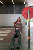 Person standing in a modern indoor setting with a red circular object and metallic pole.