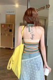 Woman with a tattoo on her back walking into a building with a yellow bag.