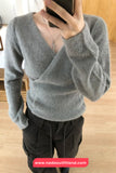 Person wearing a gray sweater and black pants, taking a mirror selfie.