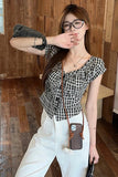 Woman wearing a checkered top and white pants in a wooden interior setting