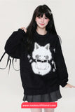 Person wearing a black sweater with a white cat design, standing against a plain background.
