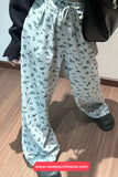 Light blue floral-patterned pants worn by a person on a wooden floor.
