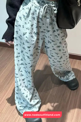 Light blue floral-patterned pants worn by a person on a wooden floor.