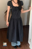 Person wearing a black checkered dress with a plain background