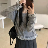 Person wearing a gray cardigan with checkered details, taking a mirror selfie.