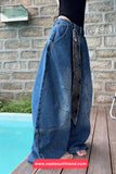 Person wearing blue jeans with a patterned patch, standing by a poolside.