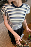 Person wearing a striped shirt and black skirt, holding a small bag with a leopard print pattern.
