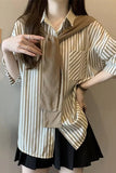 Person wearing a beige and white striped shirt with a black skirt against a neutral background