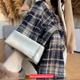 Person wearing a plaid coat with white fur trim indoors