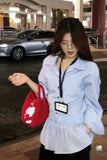 Woman in a light blue jacket with a red bag and name tag in an outdoor setting