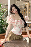 Woman wearing a floral off-shoulder top and beige skirt in an outdoor setting.
