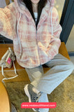 Person wearing a plaid hoodie and gray pants sitting on a wooden chair.