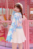 Woman wearing a colorful cardigan and white skirt in front of a pink carousel.