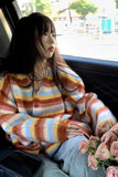 Person wearing a colorful striped sweater sitting inside a vehicle with flowers.