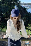 Woman wearing a blue cap and white blouse with a scenic background