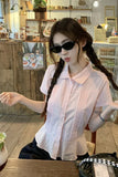 Woman wearing sunglasses and a light pink shirt in a casual setting