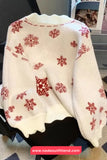 White sweater with red snowflake patterns draped over a chair.