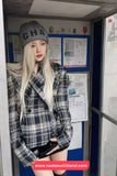 Person wearing a plaid jacket and gray beanie inside a booth with posters on the wall.