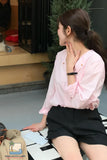 Woman in a pink shirt and black shorts sitting on a piano keyboard.
