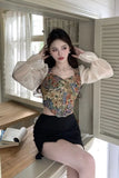 Woman sitting on a window sill wearing a floral top and black skirt.