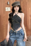 Woman wearing a denim top and jeans with a cap, standing against a wooden wall.
