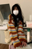 Person wearing a colorful striped sweater and face mask in an indoor setting