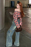 Woman in plaid shirt and jeans standing in an urban setting