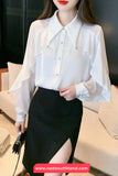 Person wearing a white blouse with ruffled sleeves and a black skirt in an indoor setting.
