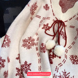 White sweater with red snowflake pattern and white pom-poms on a black background
