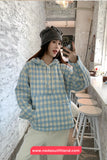 Person wearing a blue and white checkered hoodie taking a mirror selfie in a casual setting.