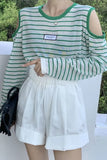 Person wearing a green and white striped shirt with cut-out shoulders and white shorts, standing outdoors.
