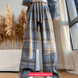 Person wearing plaid pants standing indoors with decorative elements in the background