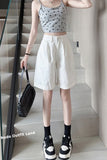 Person wearing a polka dot crop top and white shorts, holding a black handbag on a staircase.